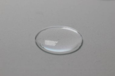 Gri arkaplandaki su damlasının makro yakın çekimi. Laboratuvar testleri ve analizleri için sıvı örneği. Hijyen ve dezenfeksiyon ürünleri