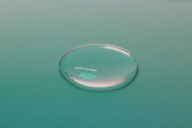 Renk arkaplanındaki su damlasının makro yakın çekimi. Laboratuvar testleri ve analizleri için sıvı örneği. Hijyen ve dezenfeksiyon ürünleri