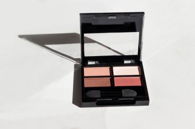 Yüz makyajı ürünleri, beyaz arka planda göz farı. Güneş ışığı ve sert gölgeler. Süper manzara..