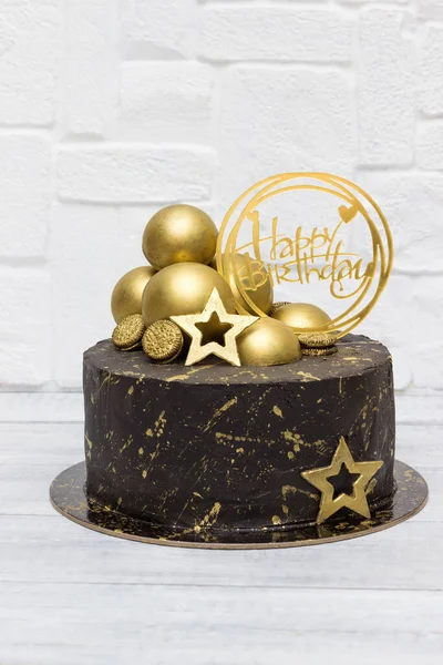 Chocolate birthday cake with gold decor.
