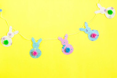 Paskalya dekoru. Sarı arka planda tavşanlı çelenk.