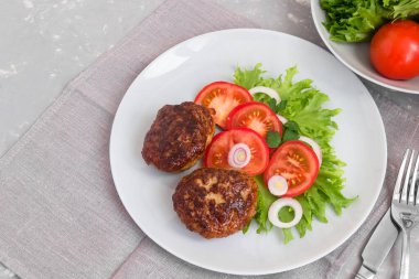 Kızarmış et, domates ve tabakta salata..