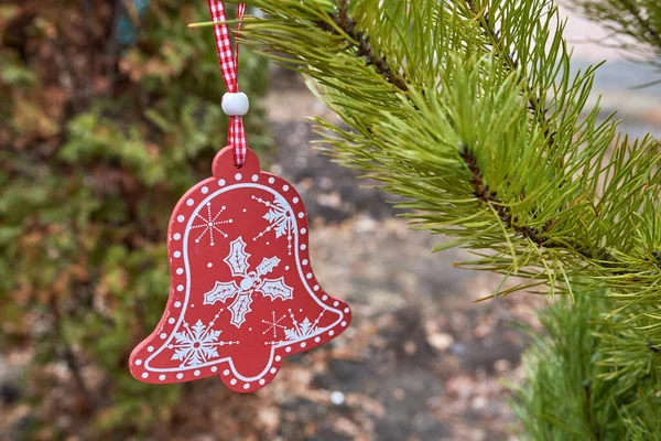 Albero di Natale giocattolo campanello di legno rosso appeso sull'abete. Focus ravvicinato e selettivo — Foto Stock