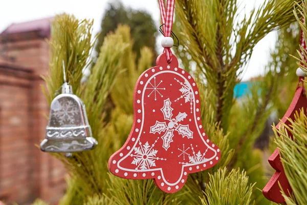 Albero di Natale giocattolo campanello di legno rosso appeso sull'abete. Focus ravvicinato e selettivo — Foto Stock