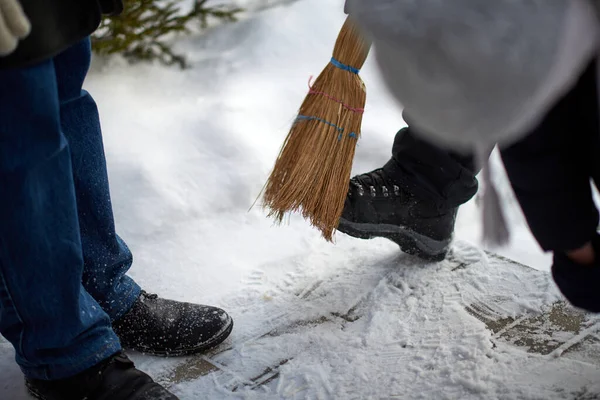 Someone is brushing snow from boots with a broom