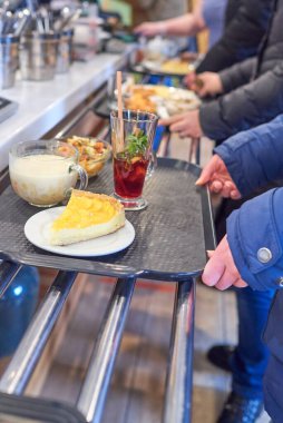 Gastronomik kafedeki kasadaki kuyruk. Yemek odasındaki dağıtım hattı. Tabakları olan tepsiler Bain Marie 'den metal raylar boyunca hareket eder.