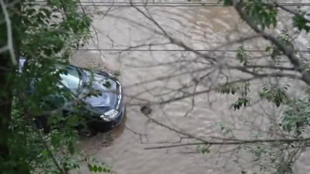 Astrakhan, Rusko - 05.31.2021: Po dlouhém přívalu deště proplouvá auto obrovskou kaluží vytvořenou na městské ulici — Stock video