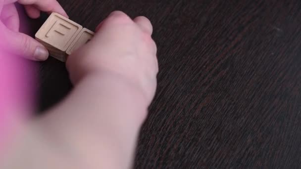 Een vrouwelijke hand bouwt woord broos met houten kubussen. Concept — Stockvideo