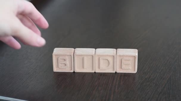 Female hands change first letter in word bide so that it turns to fide. Concept — Stock Video