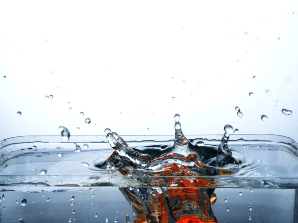 Dalgalı bir su yüzeyine büyük bir yağmur damlası düşer. Bir sürü sıçrama olur. Suyun içinde süzülürler.