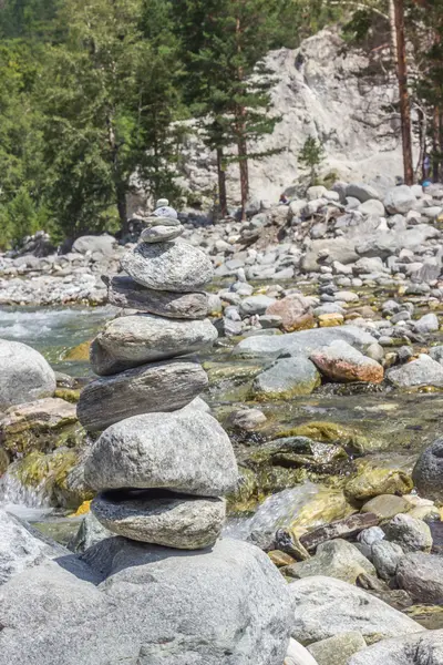 Pirámide de piedras en la orilla del río contra — Foto de Stock