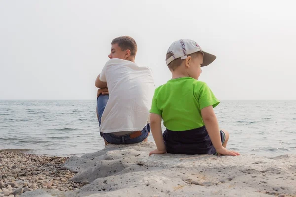 Çocuklar gölün kıyısında oturmak.