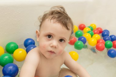 Renkli topları ile banyoda bebek.