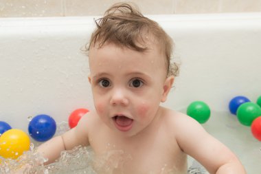 Renkli topları ile banyoda bebek.