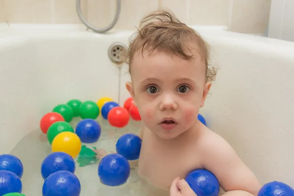 The baby in the bathroom with colored balls. — Stock Photo, Image