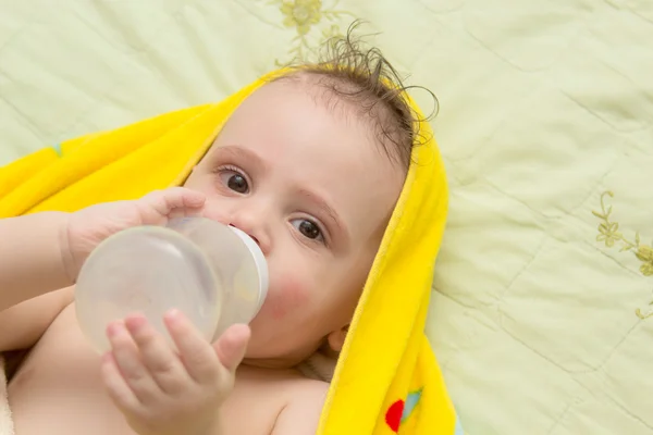 El bebé mientras está acostado come de un biberón. . — Foto de Stock