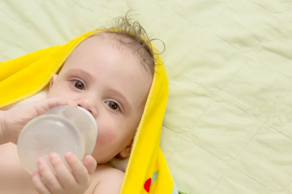 Le bébé couché mange d'un biberon . — Photo