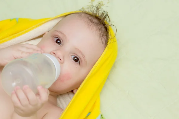 The baby while lying eats from a bottle. — Stock Photo, Image