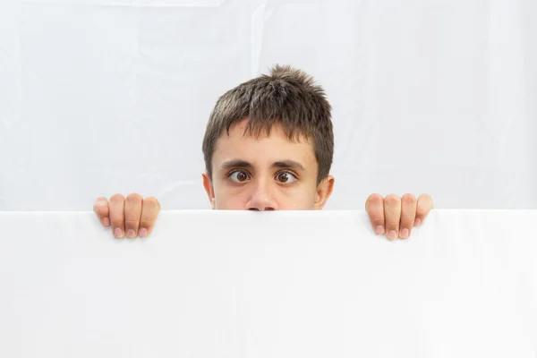 Teenage boy on a white background looking out at half of the face Royalty Free Stock Photos