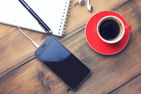 kahve, telefonu, kulaklık, defter ve kalem masada