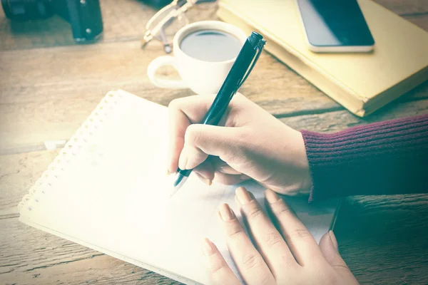 Escritura de la pluma de la mano de la mujer en el cuaderno en mesa de trabajo —  Fotos de Stock