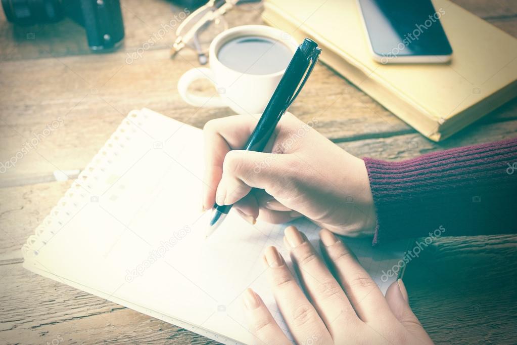 woman hand pen writing on notebook on working table