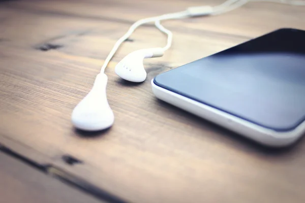 Hoofdtelefoon en de telefoon op houten tafel — Stockfoto