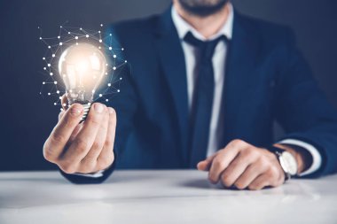 Adam arka planda ampul yakıyor.