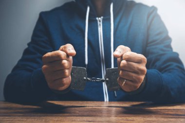 Ahşap masaya kelepçeli bir adam.