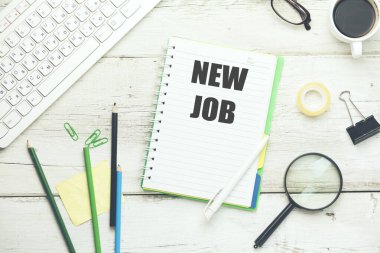 Çalışma masasında ofis malzemeleri olan not defterine yeni iş metni