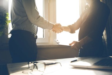 İki iş adamı anlaşma imzalamak için toplantı sırasında el sıkışıyor.