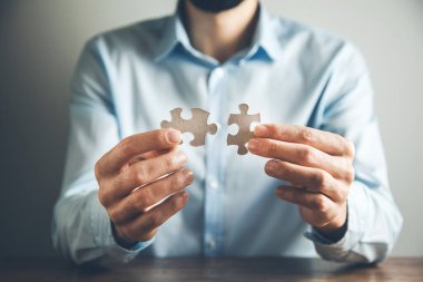 Adam iki yapboz tutuyor. 