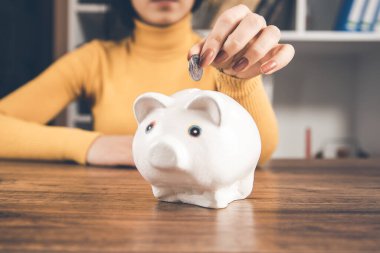 Kadın, kumbarası masanın üzerinde olan bozuk paralar veriyor.