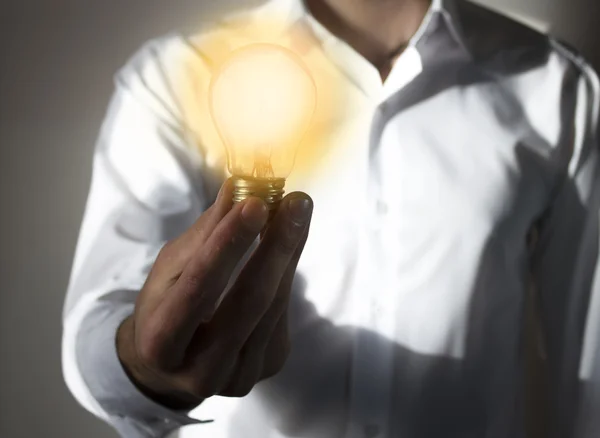 Empresario con bombilla iluminada balanceándose en su mano —  Fotos de Stock