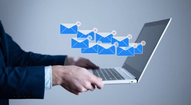 Elinde dizüstü bilgisayar ve posta simgesi olan bir iş adamı