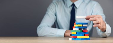 İş adamı elinde renkli tahta küp bloğu tutuyor.