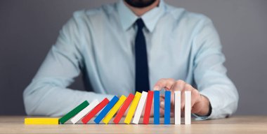 Adam parmaklarıyla domino taşlarını düşürüyor.