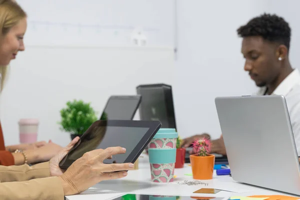 Full concentration at work. Group of young business people working while sitting at the office desk together.  Hands woman teacher or tutor with adult students in classroom at desk with black tablet.  Job and study concept.