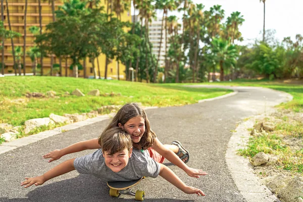 公園でロングボードを楽しんでいる愛らしい幸せな子供たち 兄と妹はスケートボードに横たわっていた スポーツと家族のコンセプト — ストック写真