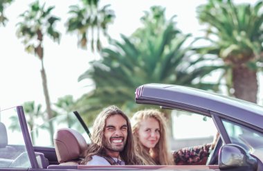 Açık yolda özgürlük. Kız arkadaşı yanında otururken ve üstü açık arabalarını sürerken ön koltukta dinlenen neşeli genç adamın yan görüntüsü. Ulaşım ve tatil kavramı.