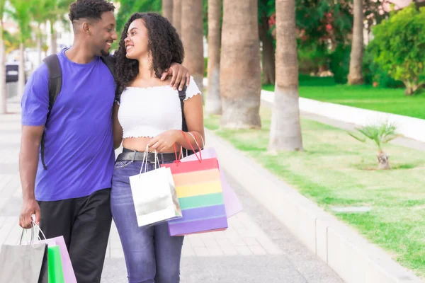 Cheerful couple in love spends time together, they walk through the city after mall center on a summer day. Love and shopping concept.