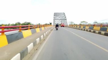 Banyumas, Central Java, Endonezya 9 Haziran 2021: Araba ve motosiklet trafiğinin ortasında Serayu Nehri Köprüsü 'nü geçen sürücüler görülüyor