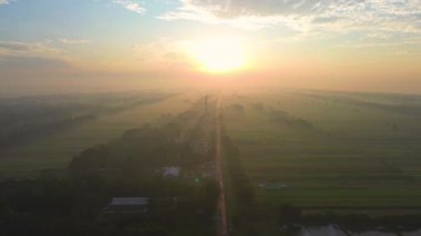 Kırsal ve tarım alanlarının ortasındaki bir otobanın insansız hava aracı görüntüsü. Altın saatin sonunda sabah güneş doğuyor.