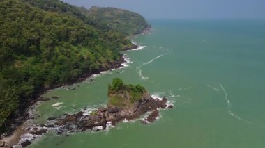 Karang Agung Sahili, Kebumen, Central Java, Endonezya 'nın insansız hava aracı görüntüsü. Kıyı şeridi yoğun ağaçlarla ve okyanustan gelen dalgalarla çevrili mercan kayalarıyla çevrilidir..