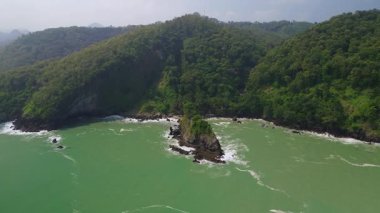 Karang Agung Sahili, Kebumen, Central Java, Endonezya 'nın insansız hava aracı görüntüsü. Kıyı şeridi yoğun ağaçlarla ve okyanustan gelen dalgalarla çevrili mercan kayalarıyla çevrilidir..
