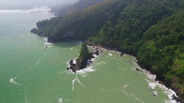 Karang Agung Sahili, Kebumen, Central Java, Endonezya 'nın insansız hava aracı görüntüsü. Kıyı şeridi yoğun ağaçlarla ve okyanustan gelen dalgalarla çevrili mercan kayalarıyla çevrilidir..