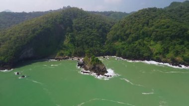 Karang Agung Sahili, Kebumen, Central Java, Endonezya 'nın insansız hava aracı görüntüsü. Kıyı şeridi yoğun ağaçlarla ve okyanustan gelen dalgalarla çevrili mercan kayalarıyla çevrilidir..