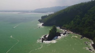 Karang Agung Sahili, Kebumen, Central Java, Endonezya 'nın insansız hava aracı görüntüsü. Kıyı şeridi yoğun ağaçlarla ve okyanustan gelen dalgalarla çevrili mercan kayalarıyla çevrilidir..