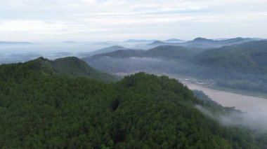 Serayu Nehri 'ni geçen demiryolu köprüsünün hava aracı görüntüsü, ormanlar ve tepeler arasında, Banyumas' da sabah sisi, Central Java, Endonezya