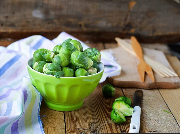 Brotes de Bruselas en un tazón sobre un fondo de madera — Foto de Stock